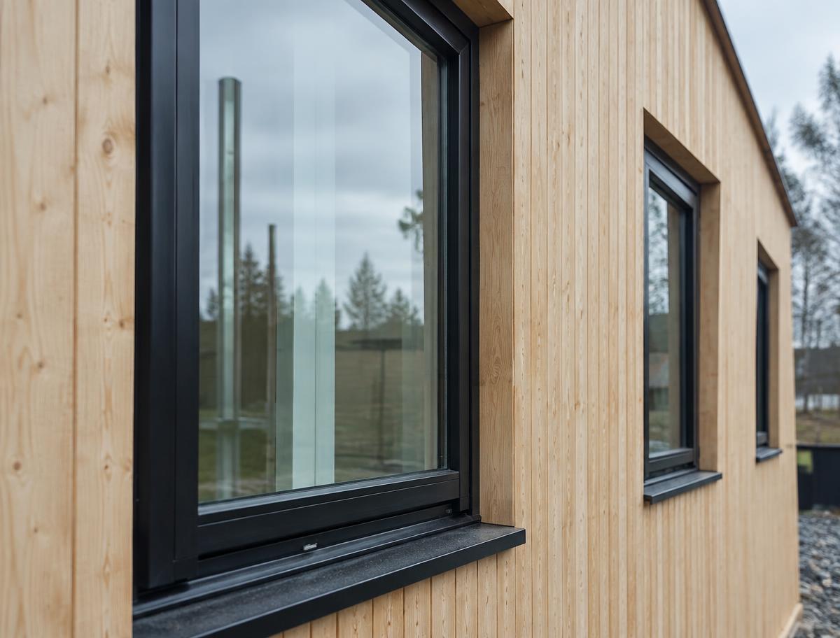 Nye sortmalede trævinduer monteret i lys træfacade